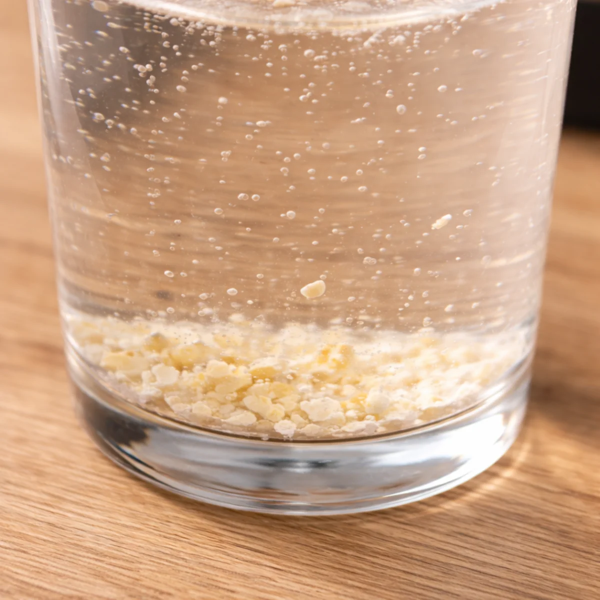 Czajnik elektryczny i szklanka z wodą, na dnie widoczny biały kamień z twardej wody